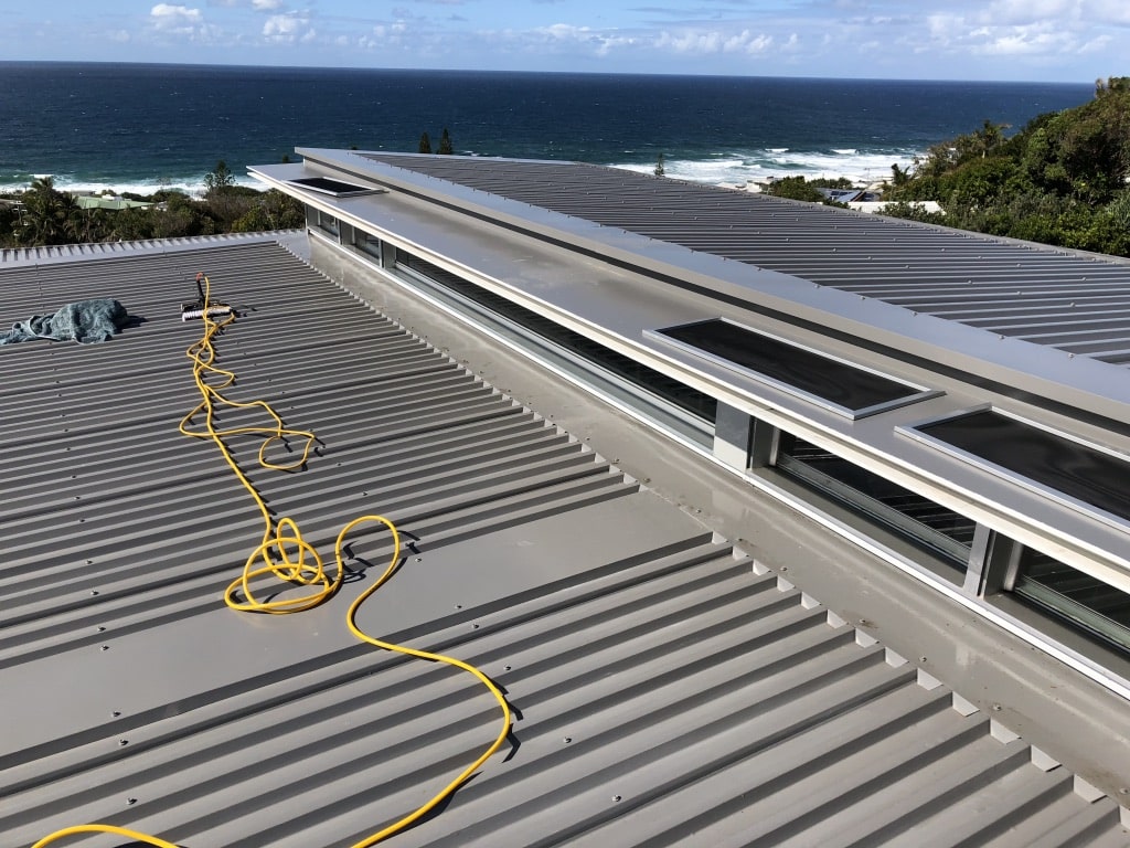 Commercial roofing with a roof cleaning brush and water pump tool