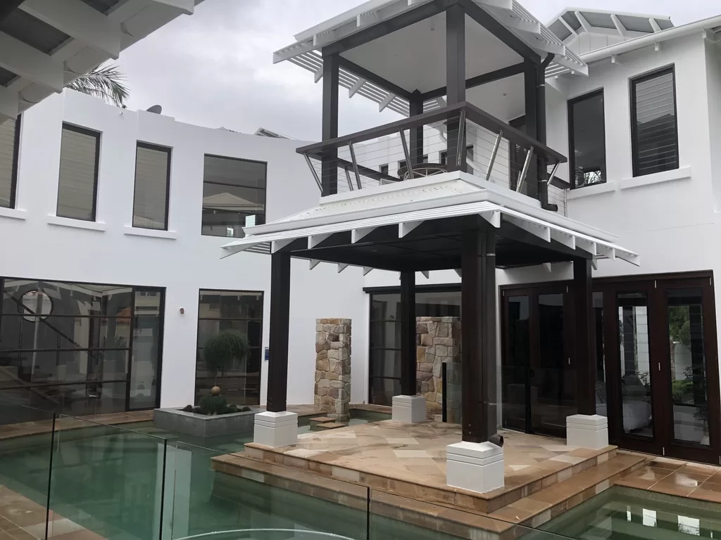 F24EB88F-12BA-4179-9D21-F6E1296DD862_1_105_c Patio surrounded by pool -- luxurious white house with clean windows