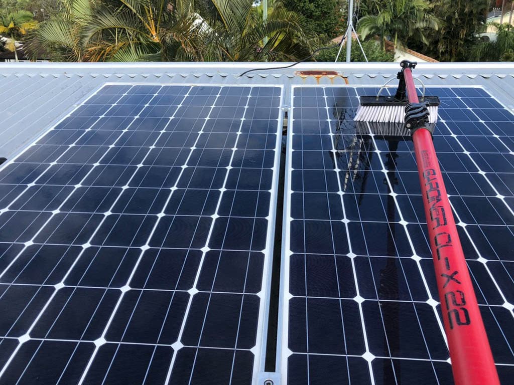 Cleaning a solar panel with a brush and water pump device